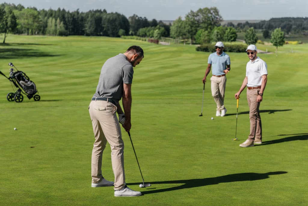 Tres hombres sanos jugando al golf en un campo de golf abierto y de exuberante vegetación. El golf es una de las muchas cosas que hacer en Hurst, Texas.