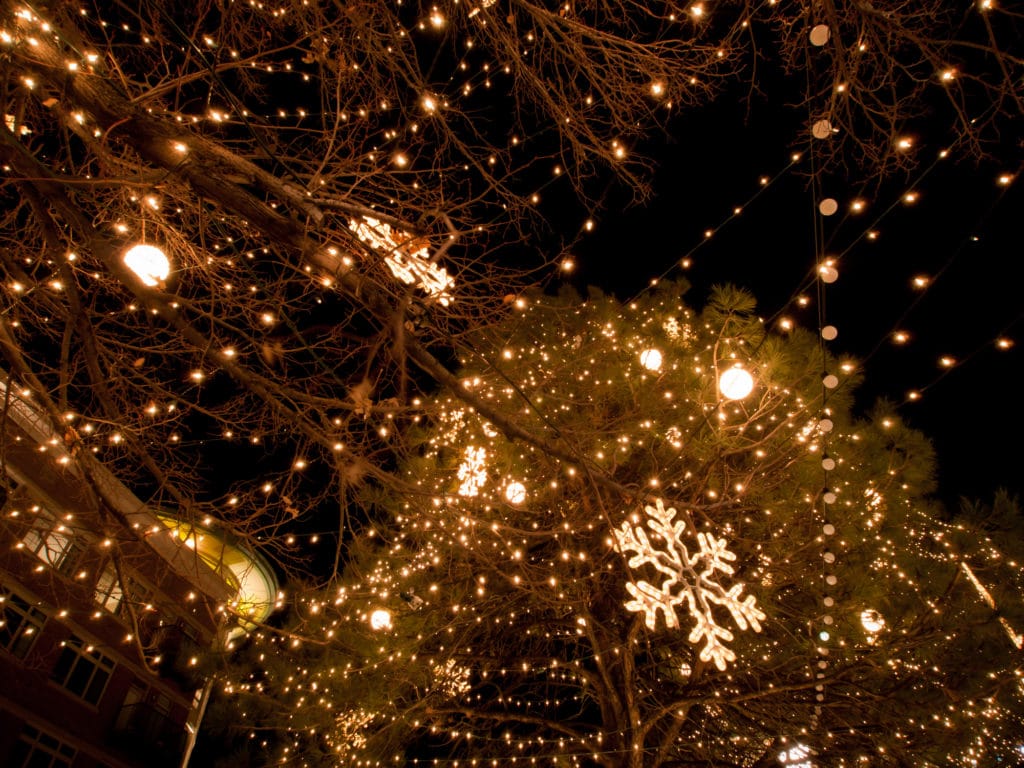 Un árbol de Navidad iluminado y otras direcciones iluminadas aparecen contra un cielo nocturno. Hay muchos eventos festivos maravillosos en Flower Mound esta temporada de vacaciones.