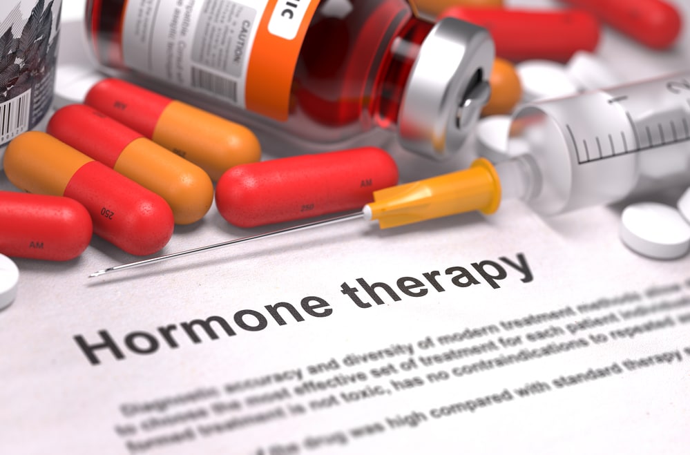 The words "hormone therapy" on a piece of paper surrounded by pills and needles. Hormone therapy, especially testosterone replacement therapy, can be complex and should be handled by a trained medical professional. Learn More.