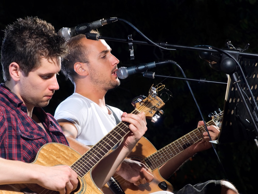 Dos guitarristas masculinos interpretan música en directo en el escenario de Lewisville.