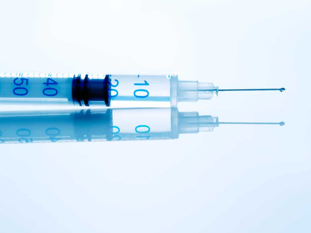 Syringe of hCG on white glossy surface. hCG is best administered via injection as part of Testosterone Replacement Therapy. Learn more.