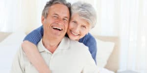 And older man and his wife laughing on a bed. Low testosterone and erectile dysfunction are closely linked. Learn more about how these two issues are related.