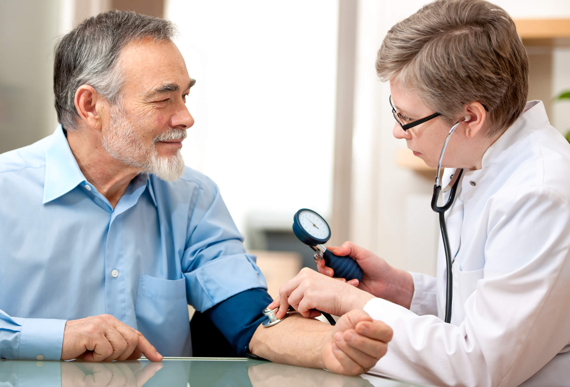 A doctor measures the blood pressure of a male patient. There is no evidence linking TRT to blood clotting events, but preventative monitoring represents best practices.