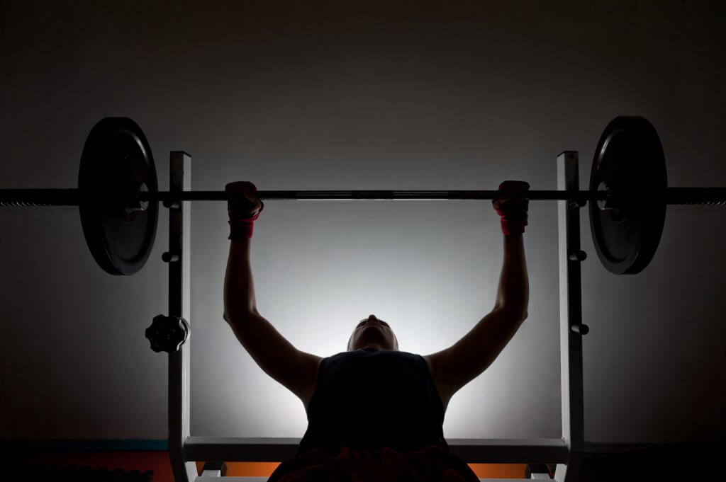 A silhouette of a man performing the bench press. Estrogen blockers are the latest method of doping for performance enhancement.