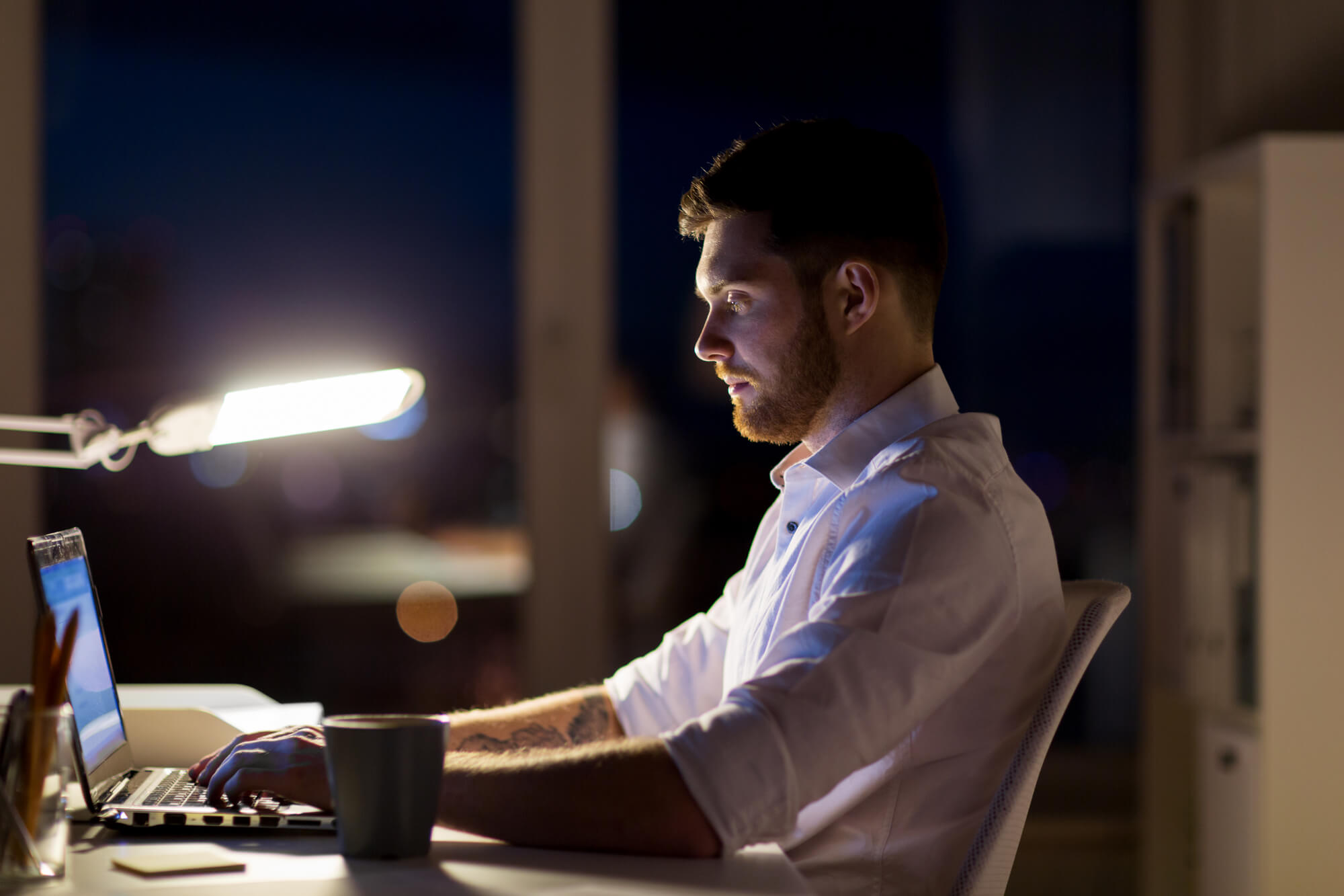 A shift worker sits at his desk at night. Shift work has been connected to low testosterone.