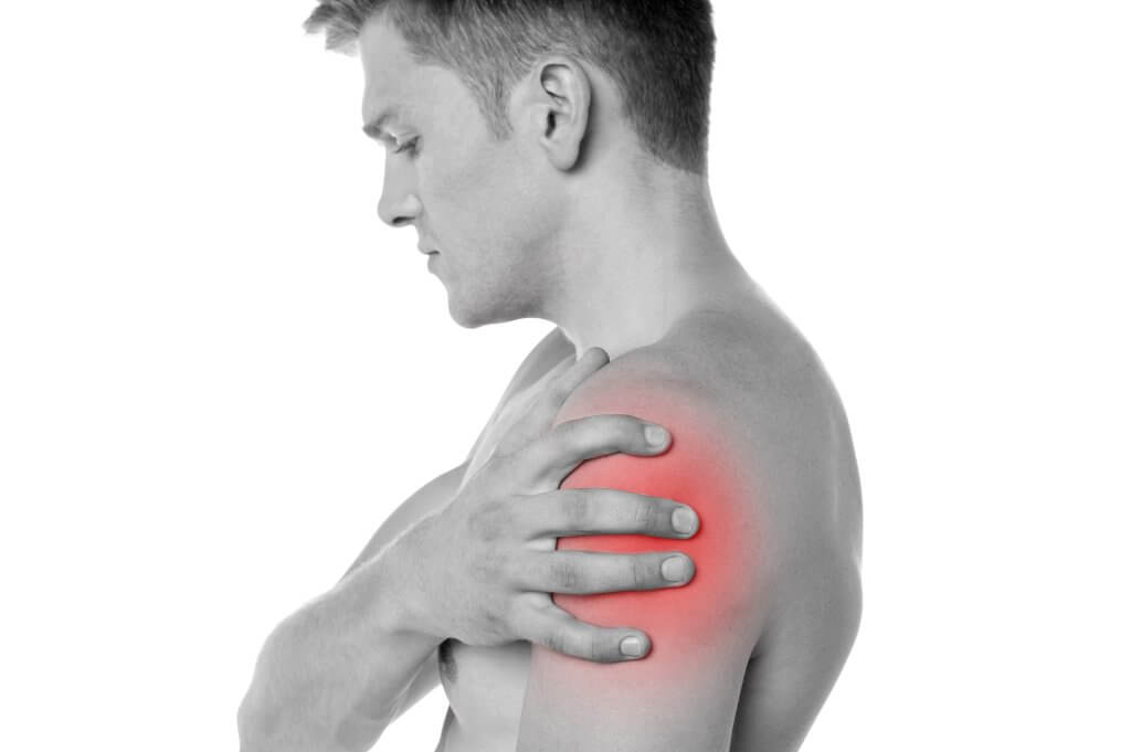 A shirtless man clutches his shoulder, which is radiating with pain. Learn the connection between joint pain and Low T.