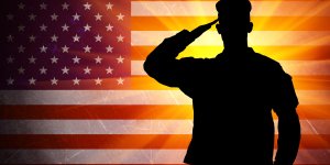 A silhouetted soldier salutes against an American Flag background. Low testosterone can be a concern for veterans due to stressful conditions.