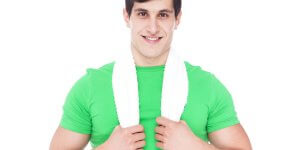A young man in a green t-shirt and a white towel around his neck looks at the camera. Does he know the Low T cutoff is different for younger men?