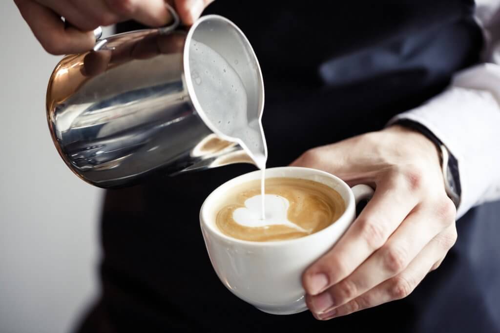A man's hands are pictured. In his left hand is a cup of coffee, and in his right is a stainless steel pitcher. He's pouring cream into the coffee. The caffeine may help his thyroid.