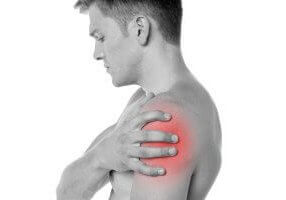 A shirtless man clutches his shoulder, which is radiating with pain. Learn the connection between joint pain and Low T.